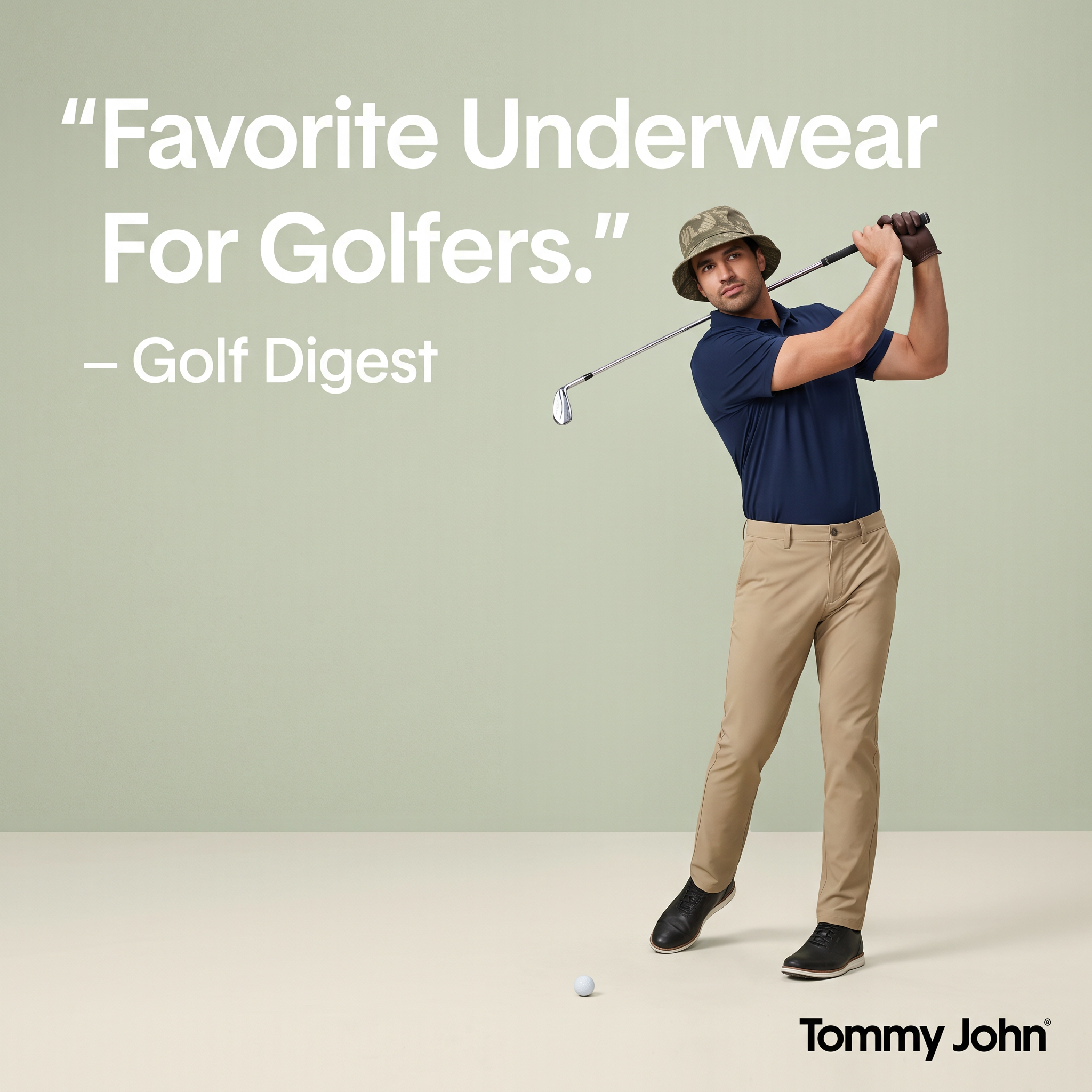 Golfer in navy polo, khaki chinos and bucket hat mid-swing on a sage green background beside a Golf Digest quote
