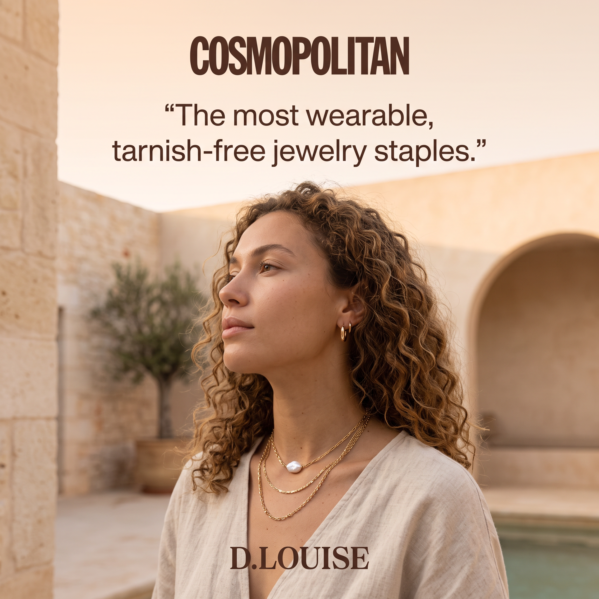 Woman with curly hair wearing layered gold necklaces and hoops in a sunlit stone courtyard under a Cosmopolitan quote.