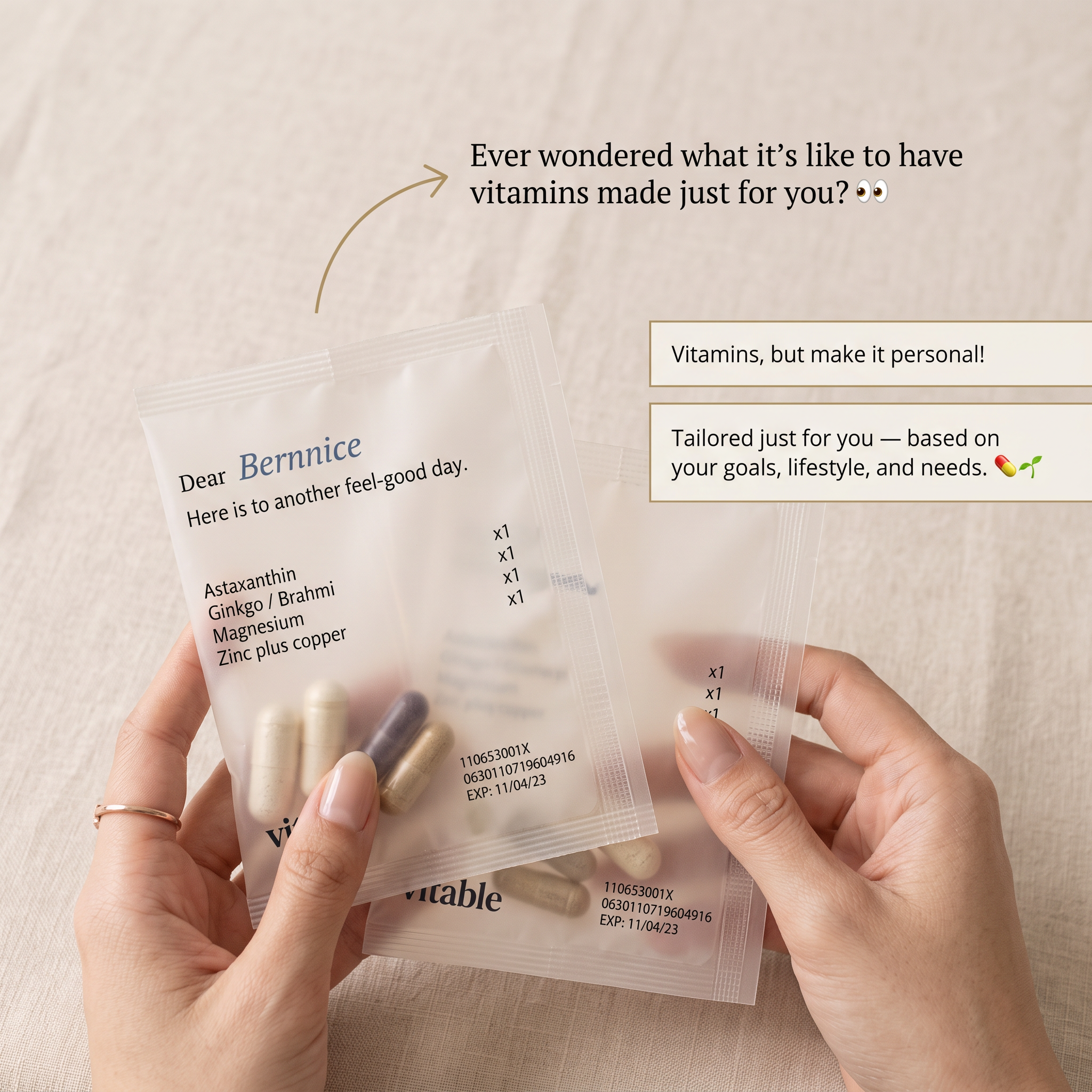 Hands holding clear Vitable vitamin sachets addressed to Bernnice with a list of capsules, on a linen background
