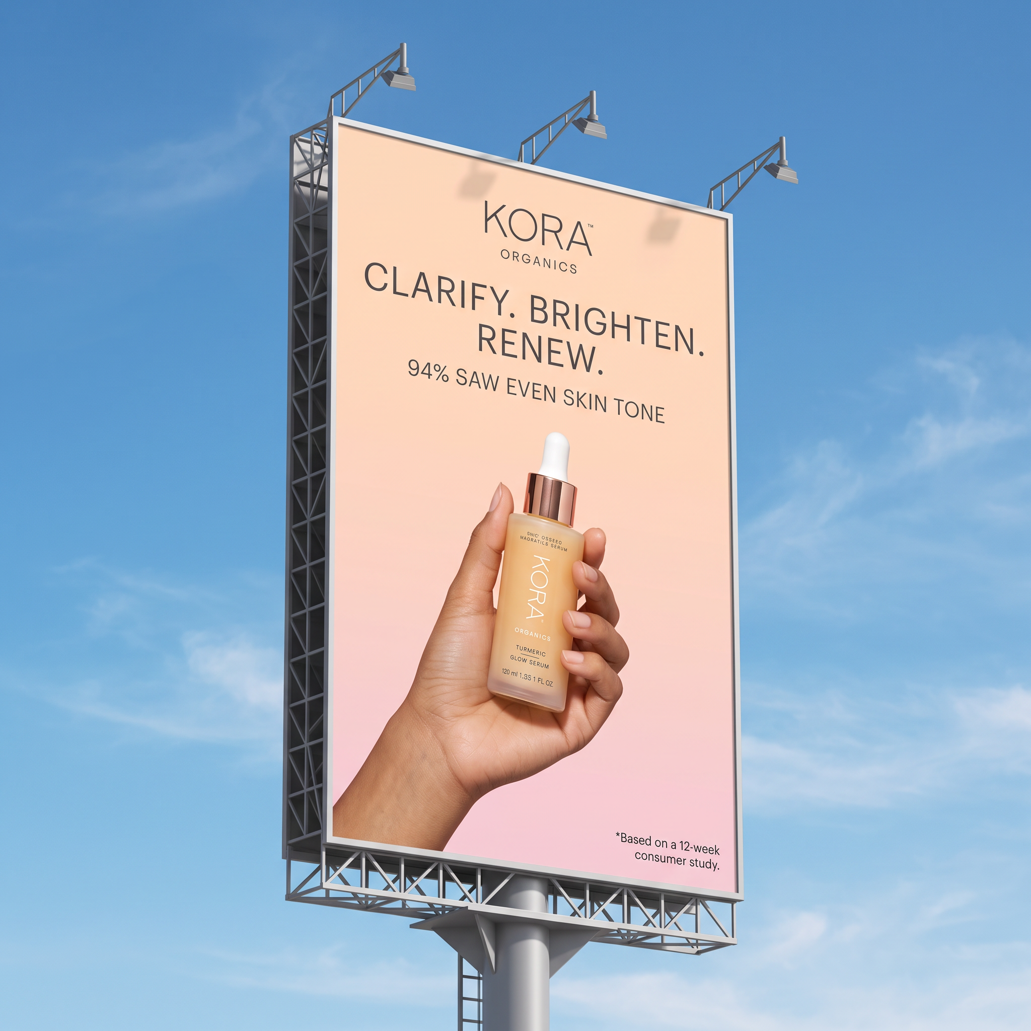Billboard against blue sky showing a hand holding KORA Organics turmeric serum with Clarify Brighten Renew headline