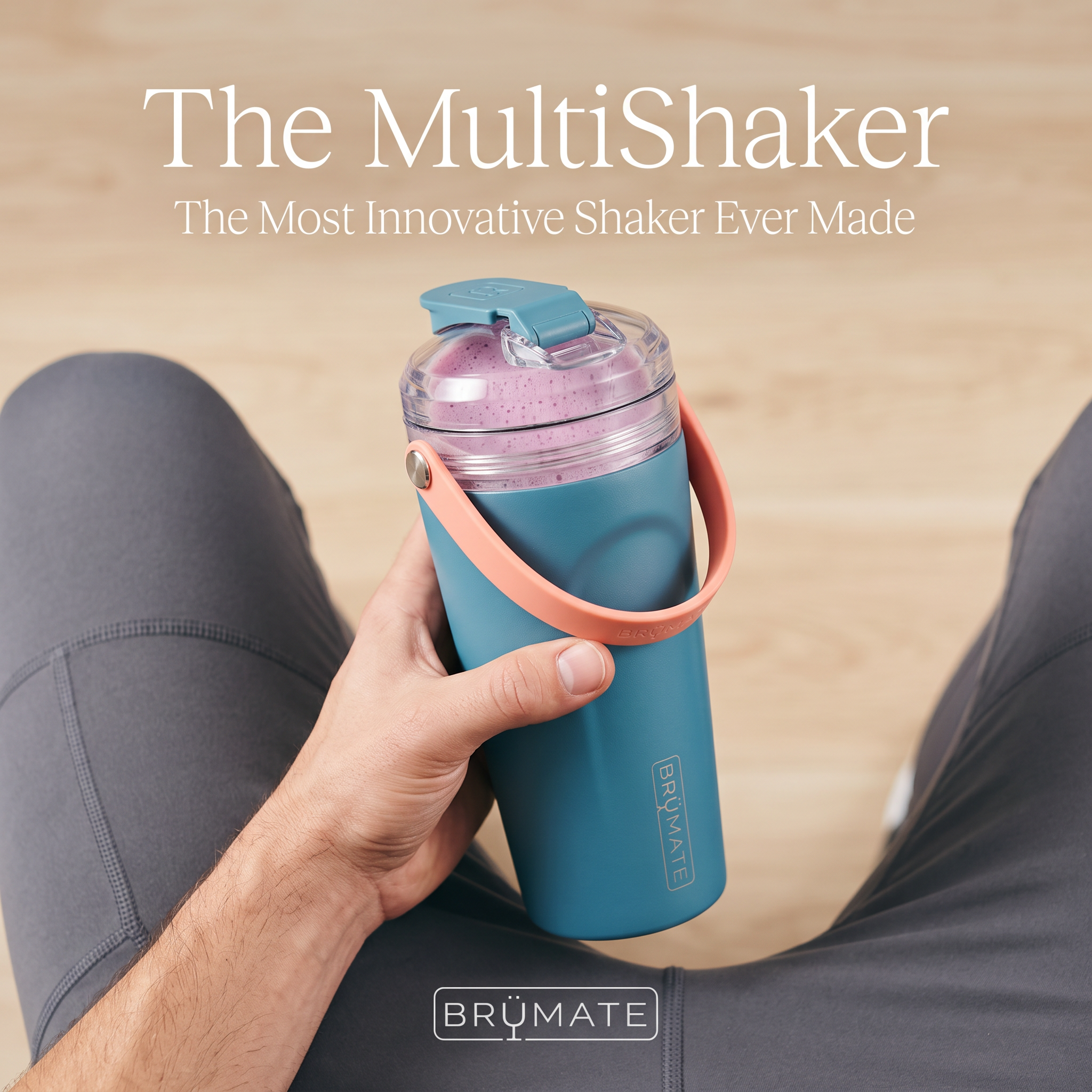First-person view of a hand holding a teal BrüMate MultiShaker with a berry protein shake over grey leggings