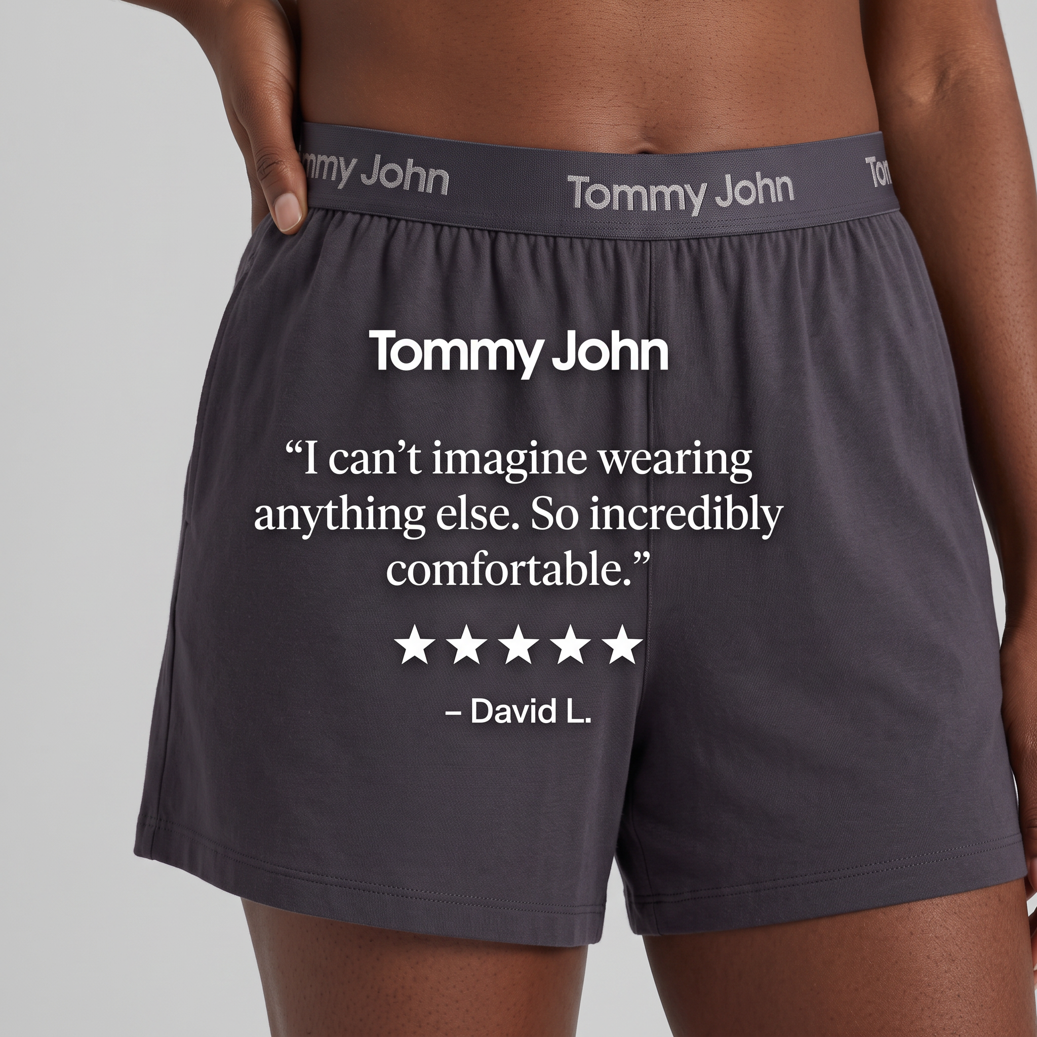 Close-up of charcoal Tommy John lounge shorts with a white five-star customer quote overlaid on the fabric