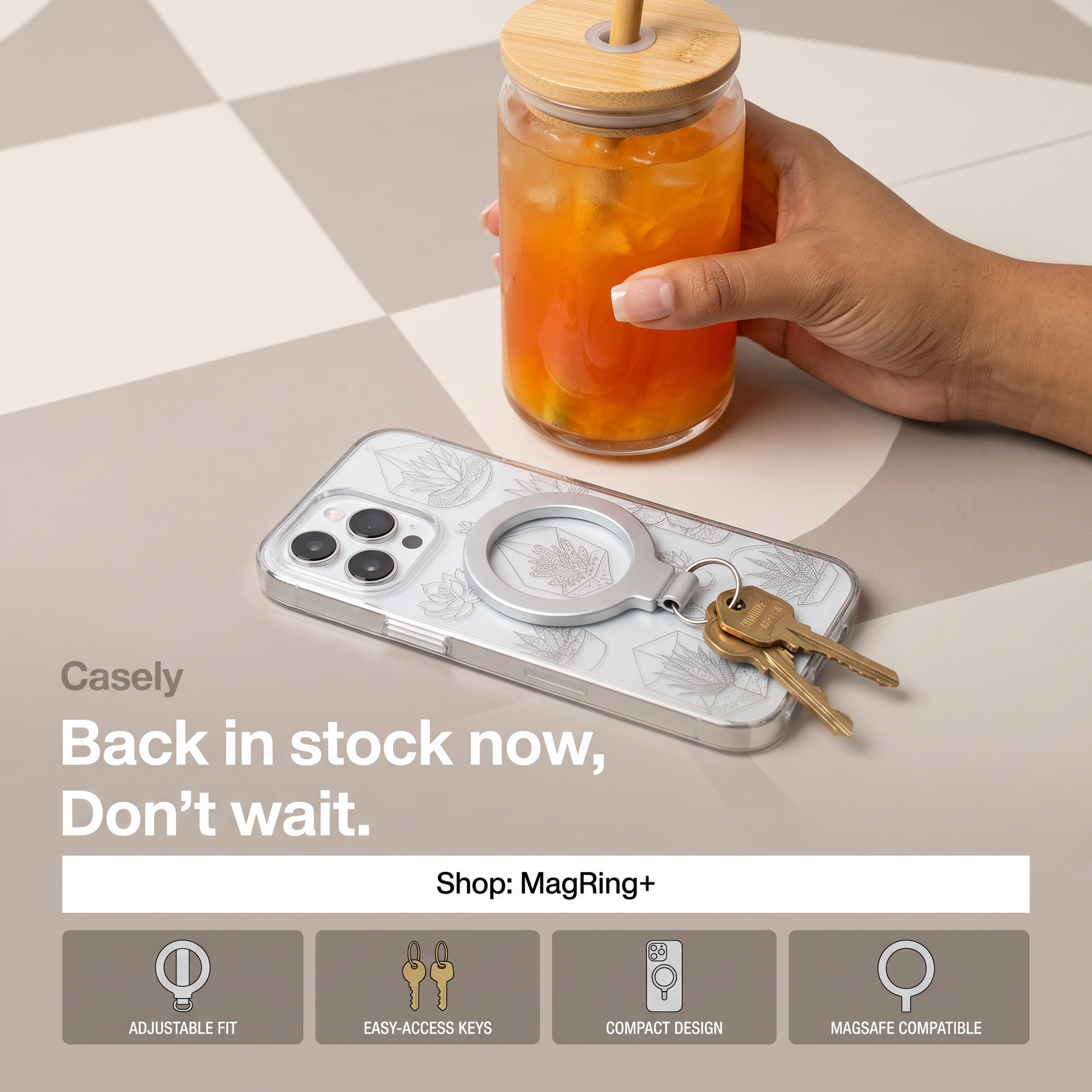 Clear patterned phone case with a silver MagSafe ring holding brass keys on a checkered table next to an iced drink
