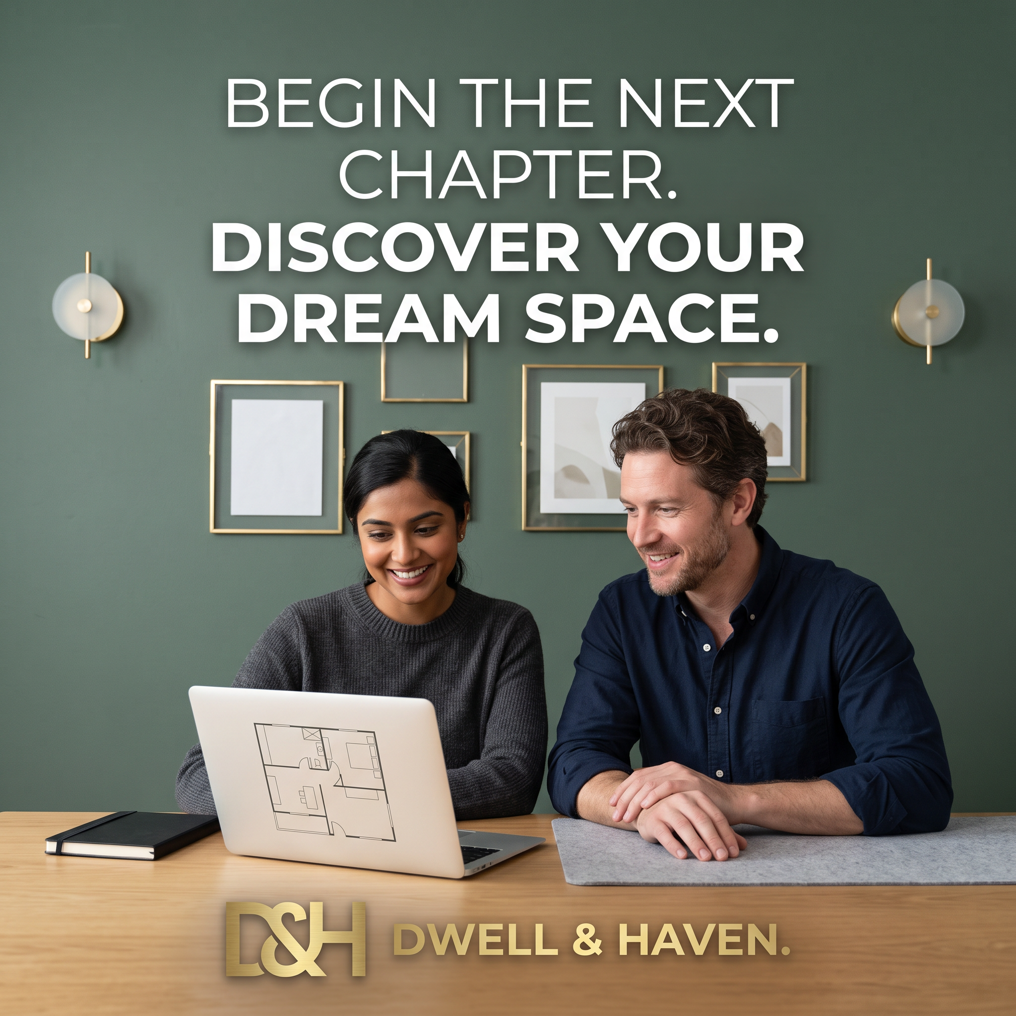 Smiling couple at a wooden desk looking at a floor plan on a laptop, in front of a sage green wall with gold frames