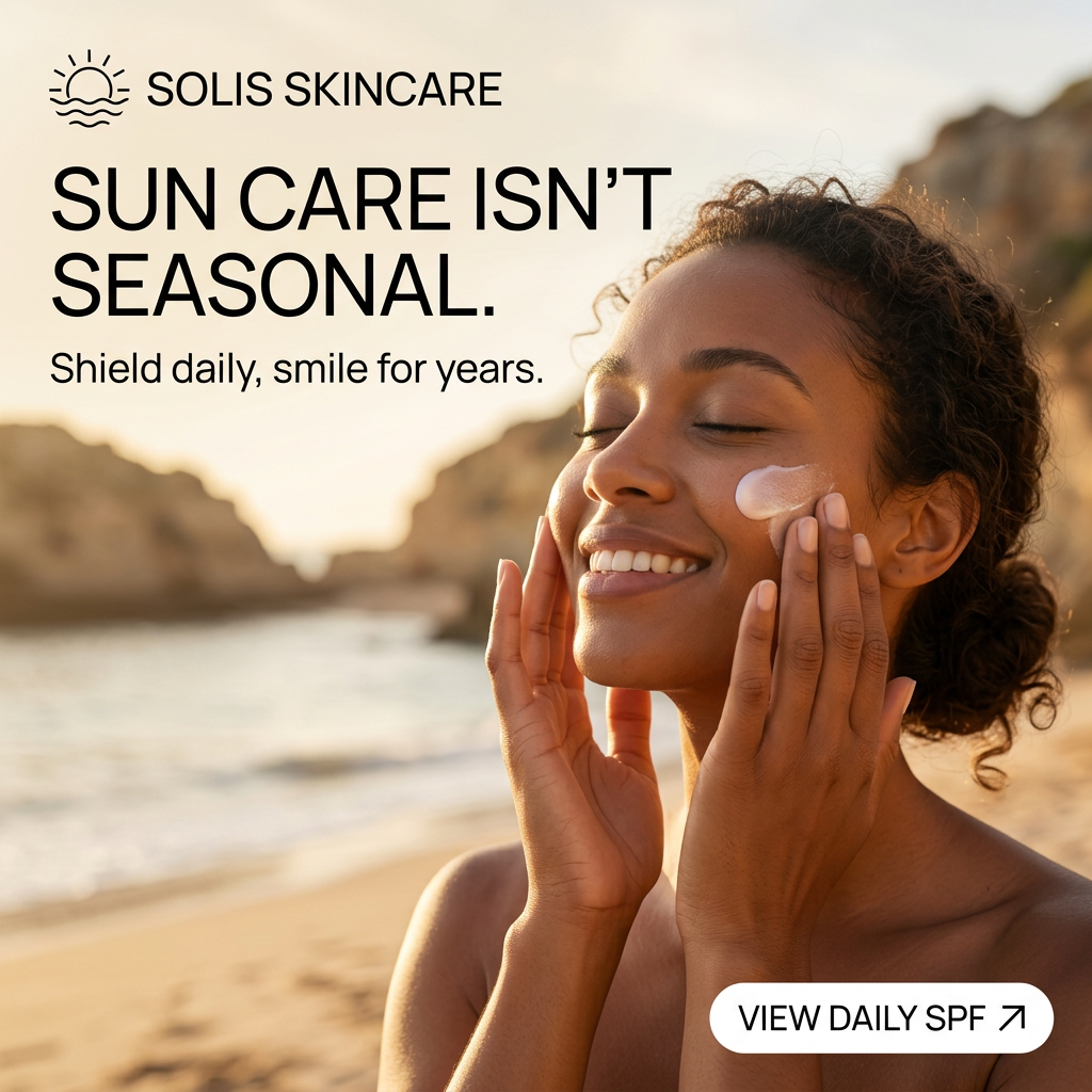 Smiling woman with closed eyes applying sunscreen to her cheek on a sunny beach with cliffs behind her