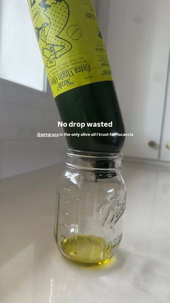 Graza Sizzle olive oil bottle upside down in a glass mason jar on a white kitchen counter, text No drop wasted