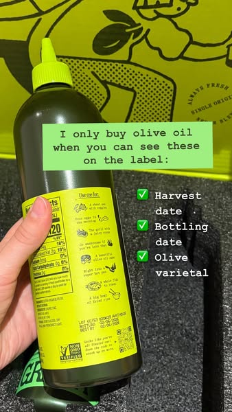 Hand holding the back label of a Graza Sizzle olive oil bottle with checklist: harvest date, bottling date, olive varietal