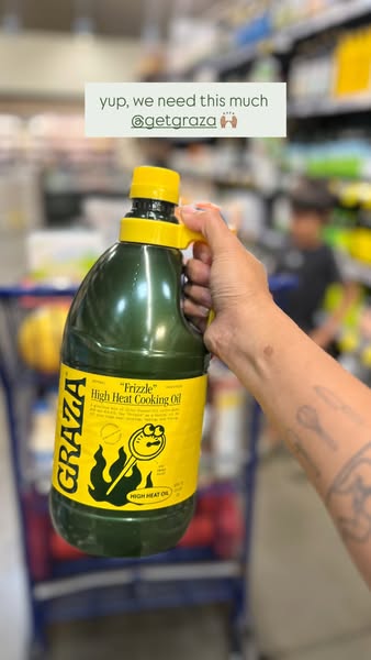 Tattooed arm holds a large Graza Frizzle High Heat Cooking Oil jug in a store aisle, caption yup, we need this much