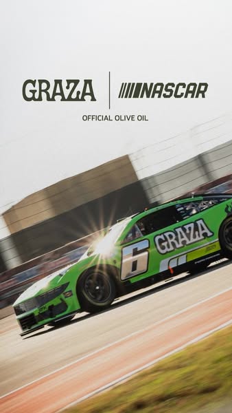 Green Graza #6 NASCAR race car speeding on track at a tilted angle with sun flare, Graza NASCAR Official Olive Oil logo