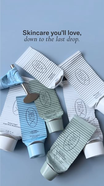 Pile of flattened, rolled-up Dieux skincare tubes in white, blue and green with a metal tube key on pale blue