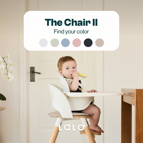 Baby eating in a white Lalo Chair II high chair with wooden legs, under a card showing six colour options