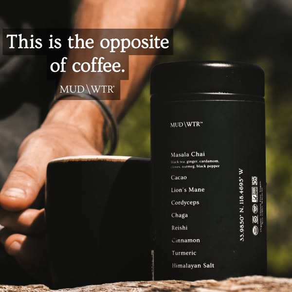 Hand reaching for a black mug beside a MUD WTR tin on a wooden log outdoors with text saying this is the opposite of coffee