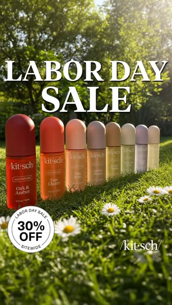 Row of eight Kitsch hair perfume bottles in a colour gradient on sunny grass with daisies and a 30% off Labor Day badge
