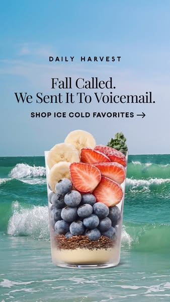 Layered smoothie glass with blueberries, strawberries and banana standing in ocean waves under a blue sky with serif headline