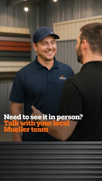 Smiling Mueller rep in navy polo talking with a customer in front of colored metal panels, text Need to see it in person?