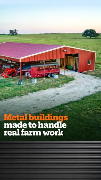 Red metal barn with open-sided canopy sheltering a tractor and livestock trailer in green pasture at sunset