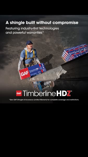 Roofer in a harness guiding a GAF Timberline HDZ shingle bundle up a ladder hoist, seen from the roof above