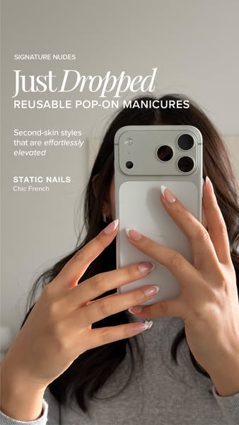 Woman taking a mirror selfie with a white phone, both hands showing nude press-on nails with white French tips
