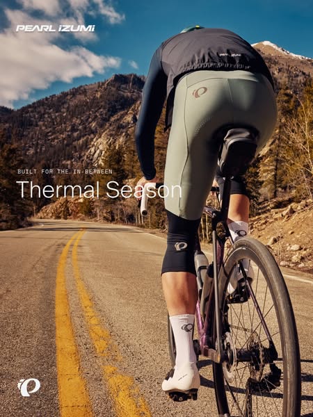 Road cyclist from behind in sage green thermal bibs and black jacket on a mountain road with headline Thermal Season