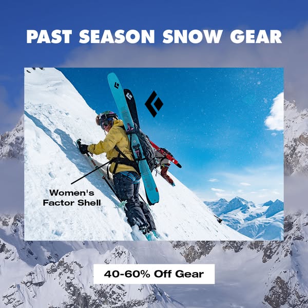 Ski tourer in yellow Black Diamond Women's Factor Shell climbing a snowy ridge with skis on pack and 40-60% off label