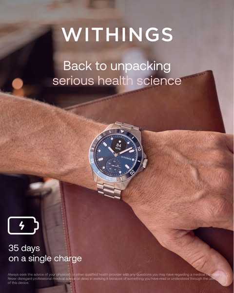 Man's wrist with Withings ScanWatch Nova blue diver watch showing 84 BPM, holding a brown leather folio, 35-day battery icon.