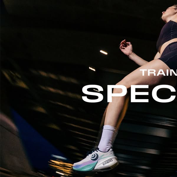Low-angle photo of a female runner mid-stride at night in white Topo Specter 3 shoes, motion-blurred city lights behind
