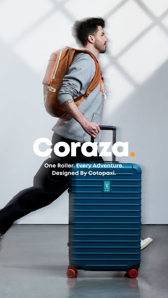 Man with brown backpack striding beside a blue Cotopaxi Coraza roller suitcase with red wheels in a bright studio
