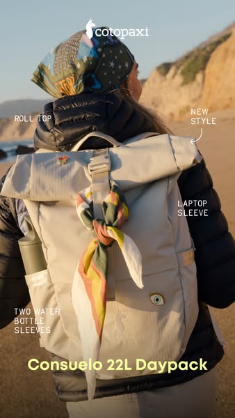 Woman on a coastal trail wearing a cream Cotopaxi Consuelo roll-top daypack with feature callouts and a scarf