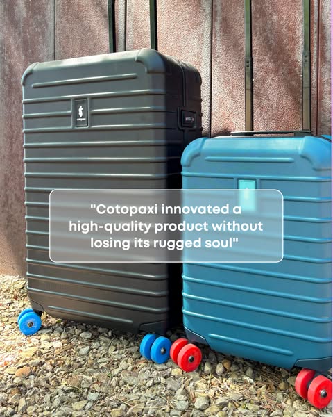 Black and teal Cotopaxi Coraza suitcases with colorful wheels on gravel with a review quote on a frosted panel