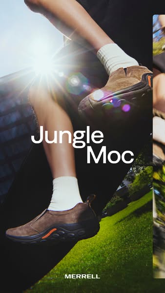 Legs in white socks wearing brown Merrell Jungle Moc slip-ons shot from below with a bright sun flare and green grass